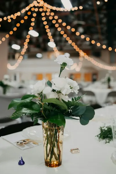 White flowers on a reception table under string lights