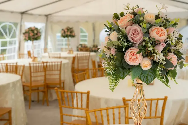 Reception tables with blush floral centerpieces under a white tent